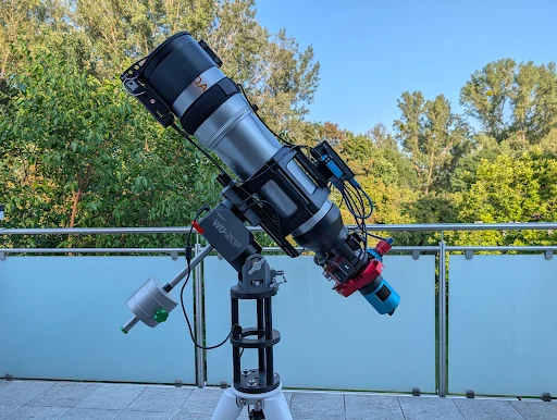 A refractor with camera, focuser and filter wheel on an equatorial mount on a balcony